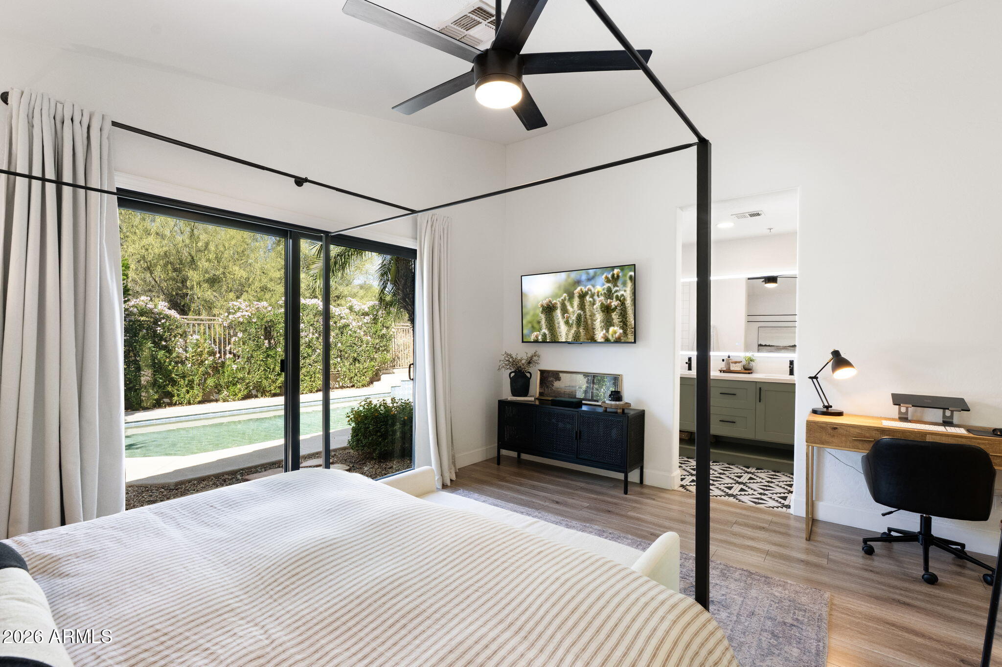 Primary bedroom after, black canopy bed, designer styling, pool view as the hero
